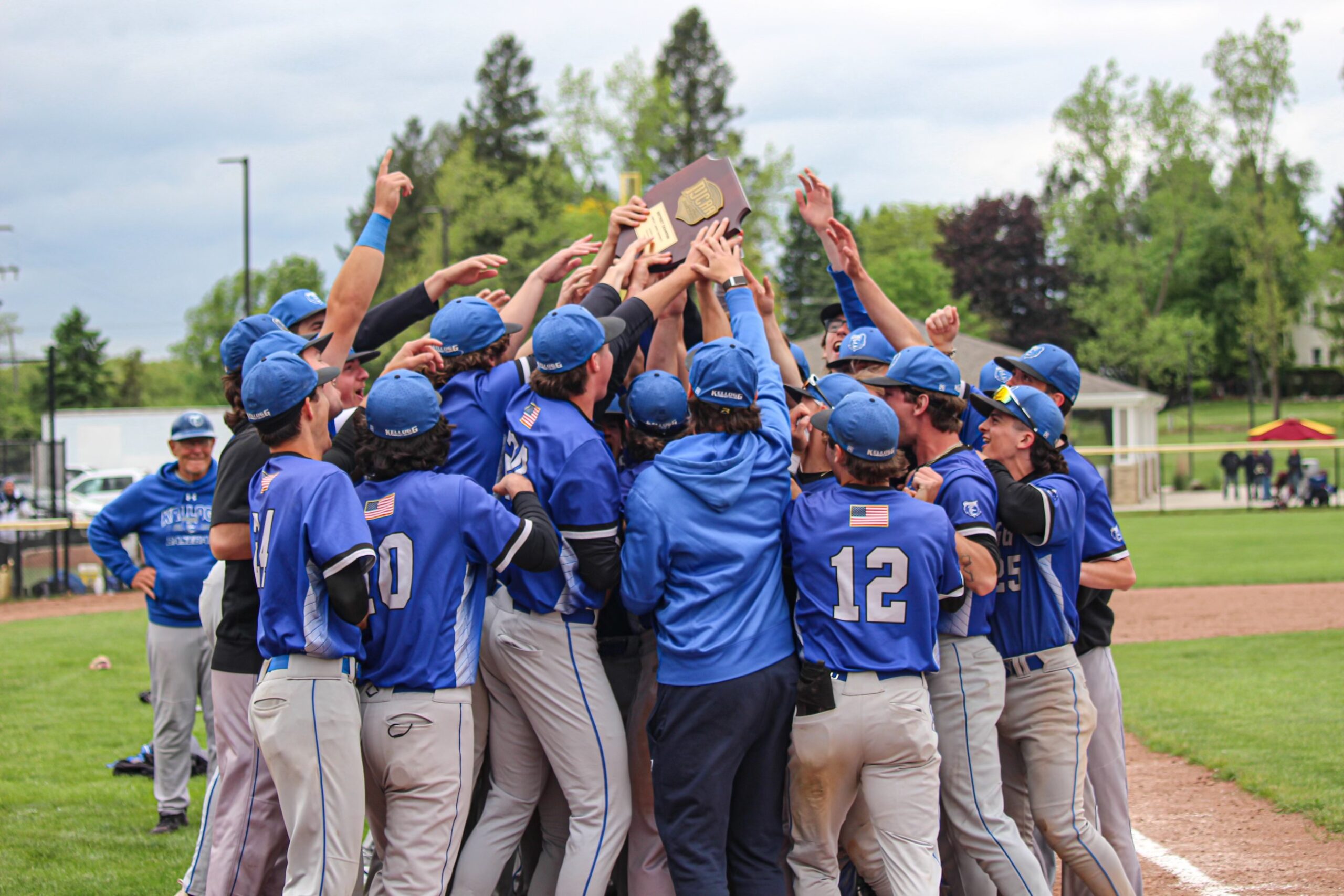 KCC baseball players huddle with the regional championship trophy.