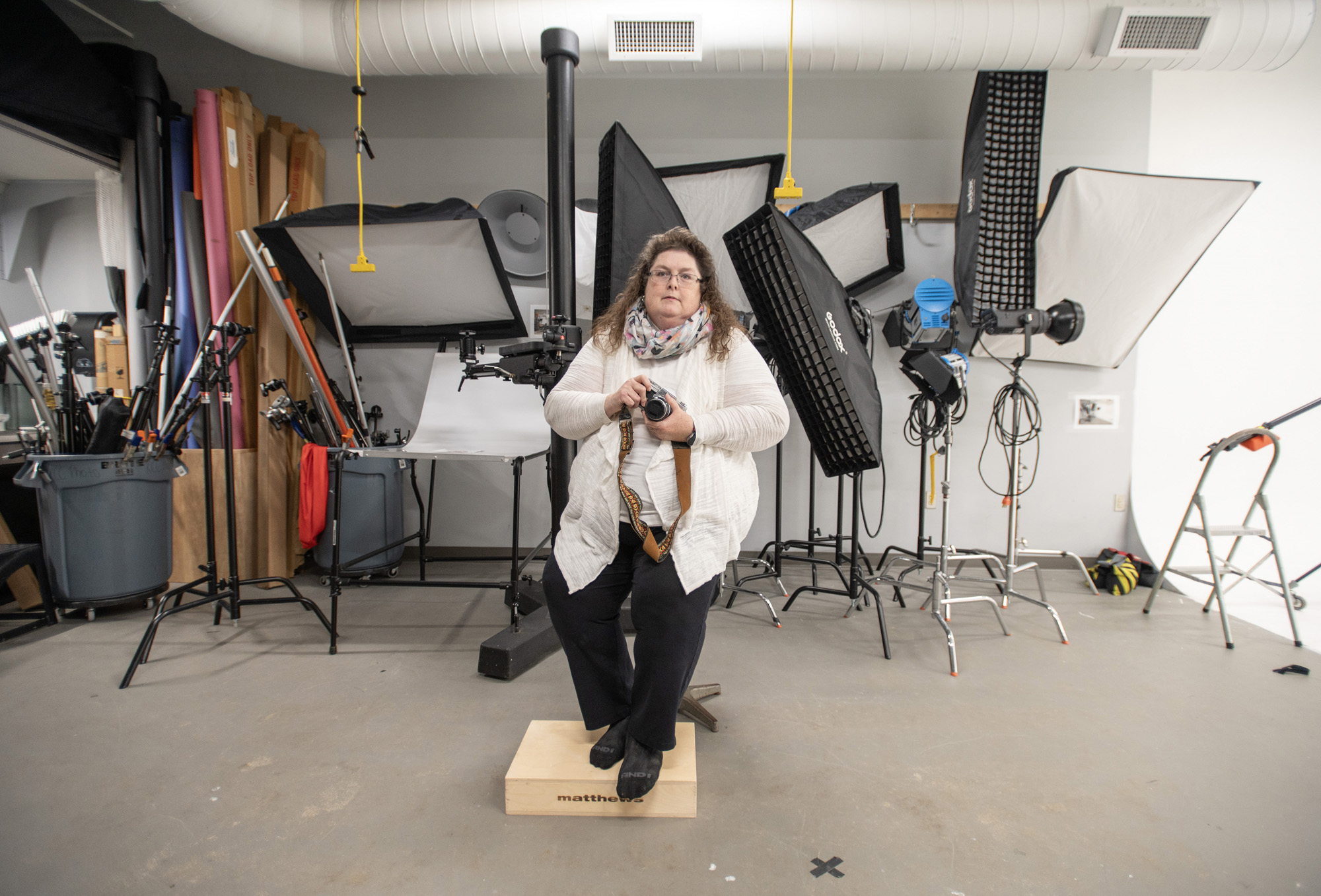 Photography student Amey M. Elkins-Little poses with a camera in the lighting lab on campus.