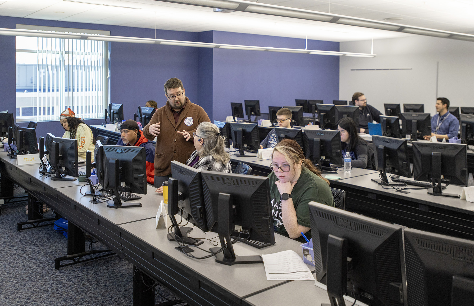 Instructors work with students in a collaborative computer lab space.