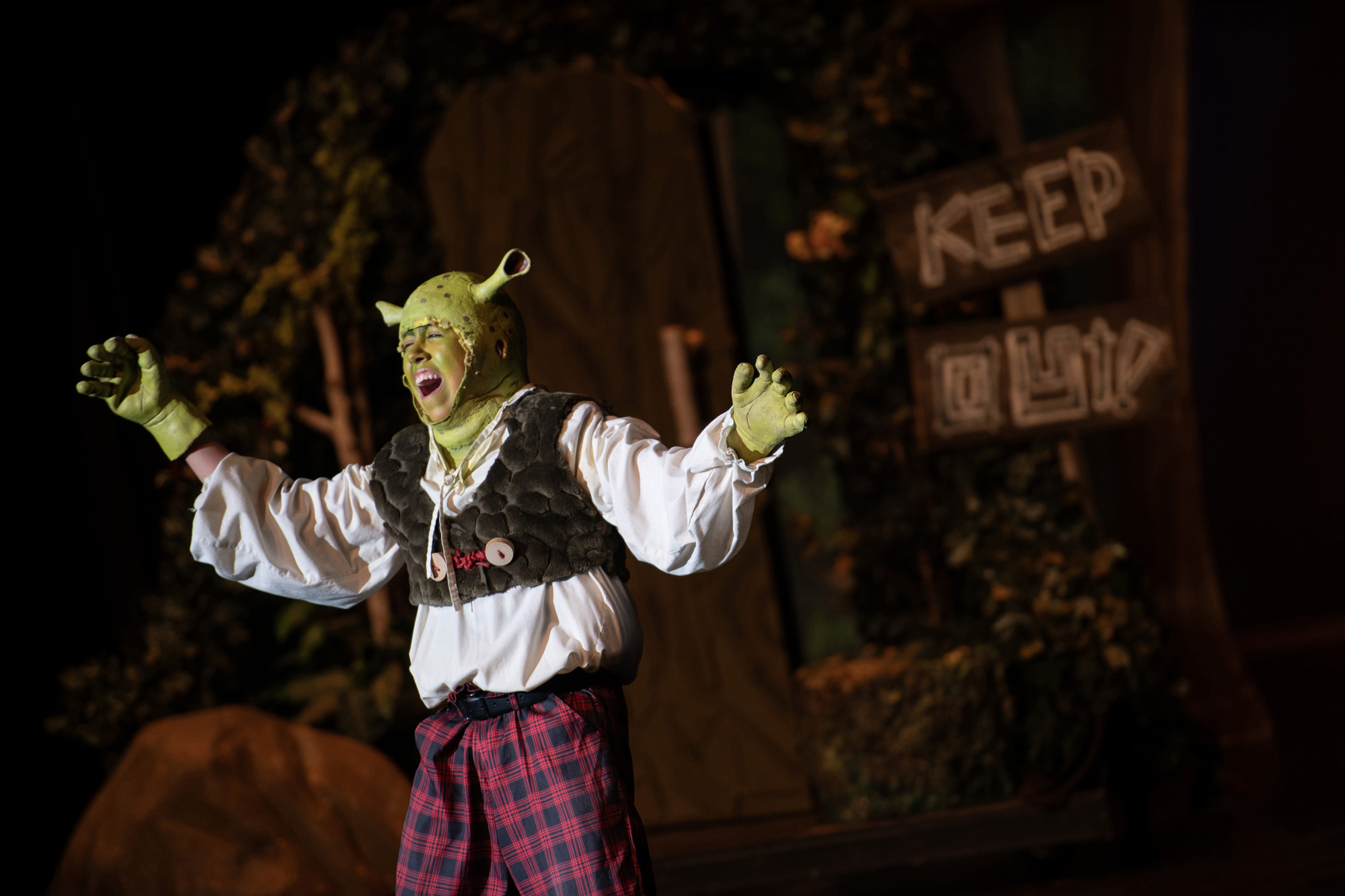 A youth camper dressed as Shrek sings during a rehearsal for "Shrek the Musical" on campus.